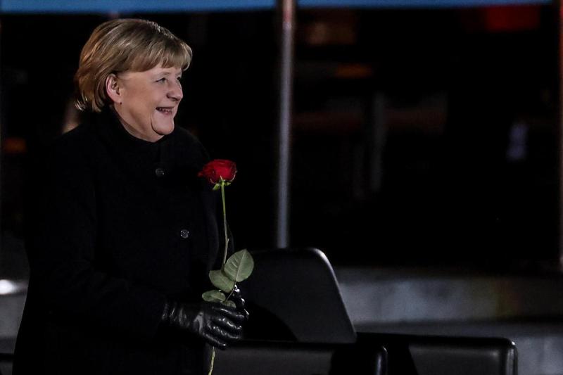 梅克爾的歌單令外界大感意外，讓德國人留下深刻印象。圖為她手持玫瑰，笑著聆聽軍樂隊演奏。 歐新社