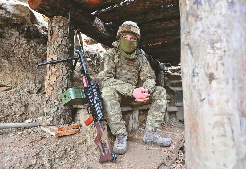 烏克蘭軍人三日於烏國頓內次克地區德爾巴切夫附近，坐在分隔親俄分離主義分子掌控地區的壕溝沿線戰鬥位置。（美聯社）