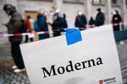 德國柏林民眾11月29日在印有「莫德納」字樣的牌子前排隊打疫苗。（歐新社）