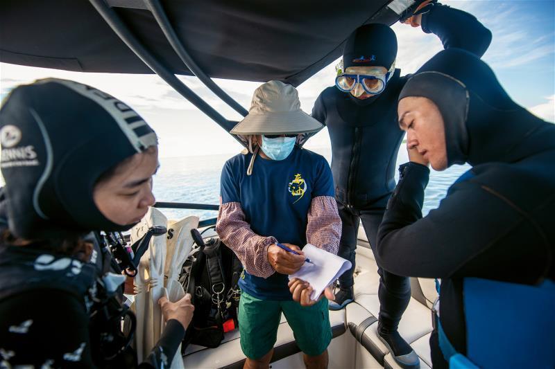 陳榮祥（中）正在跟準備潛水淨海的志工們，說明各自分配的區域和其他注意事項。
