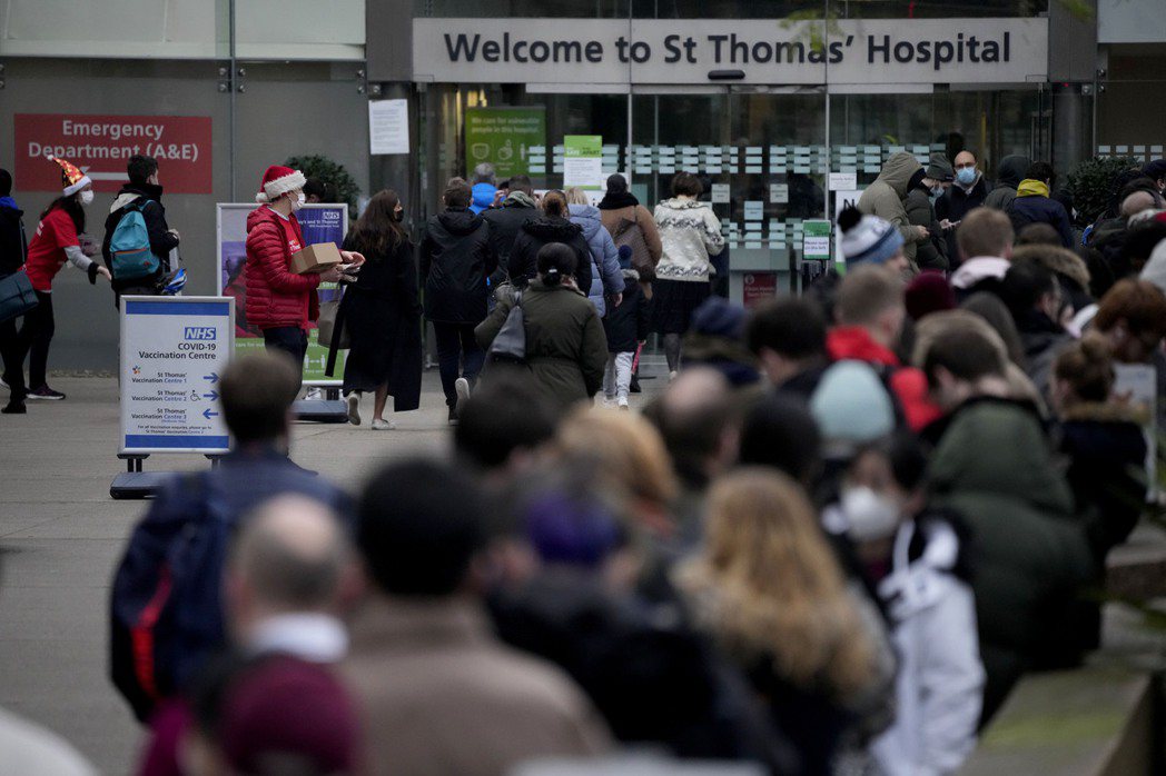 英國倫敦聖湯瑪斯醫院前等待接種加強針的人排起長隊。美聯社