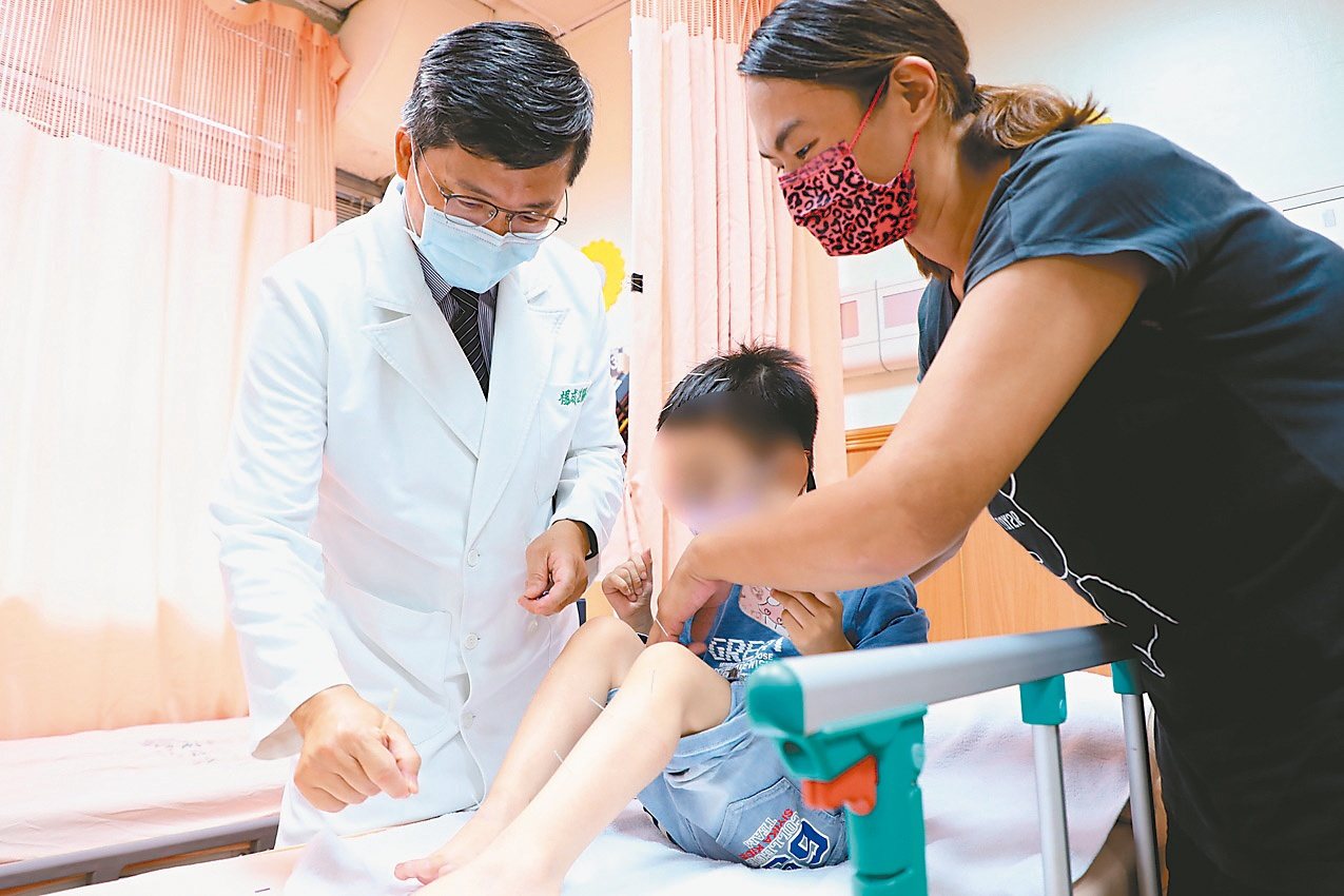 花蓮慈濟醫院中醫兒科主任醫師楊成湛（左），為林小弟針灸，活化大腦神經元，以緩解降低四肢肌肉高張力的狀況。圖／花蓮慈濟醫院提供