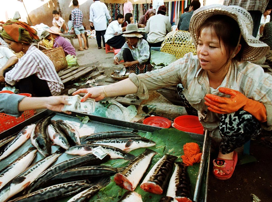 1997年金邊一名魚販接受美金付款。 圖／路透社