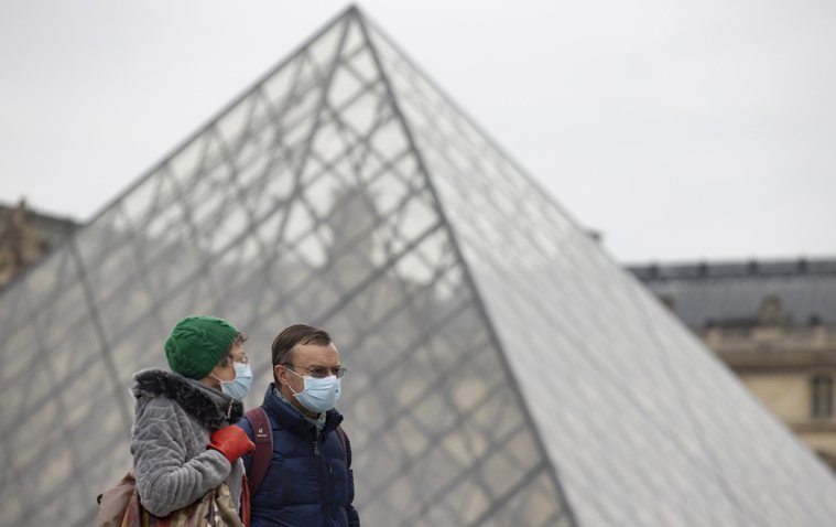 兩名路人戴口罩經過巴黎羅浮宮。圖／歐新社