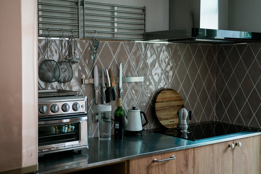 黯的藕粉色菱形磁磚，搭上收薄的不銹鋼檯面和木頭廚櫃，是理想廚房的樣子。 圖／Ev...