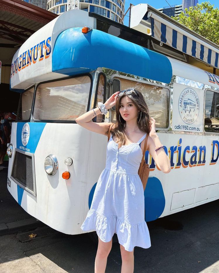 廖思惟穿Brandy Melville白色裙裝在American Doughnut Kitchen（ADK）果醬甜甜圈店前拍照。圖／取自IG