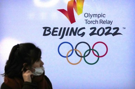一名女子經過北京冬奧聖火傳遞活動的標誌。（美聯社）