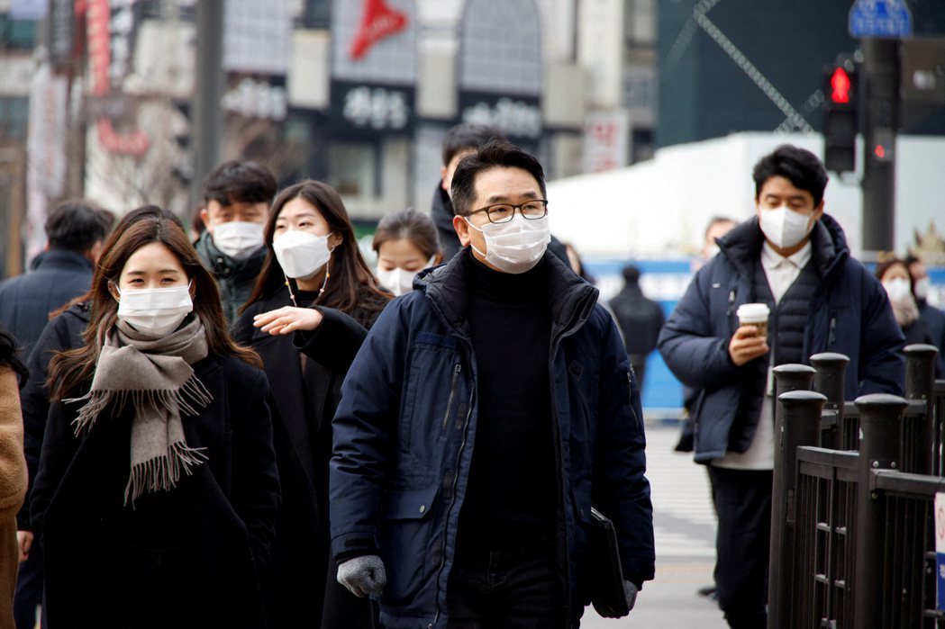 南韓首爾戴口罩民眾5日經過當地街頭。路透