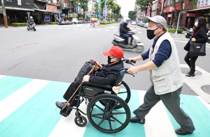 64歲的蔣昌冬雖患有小兒麻痺，仍每天推著輪椅陪著眼睛全盲的媽媽走路。深怕路口紊亂的交通與路況，蔣昌冬會推著媽媽過馬路。記者陳正興／攝影