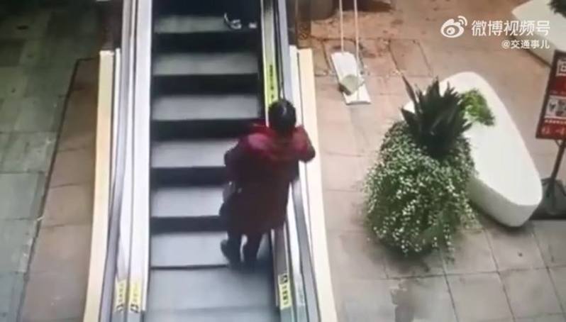 大陸日前瘋傳短片，見到1名老婦疑因搭手扶梯速度太快導致重心不穩，失衡跌倒頭朝地不斷向後翻滾，經歷了驚悚1分鐘。（圖／翻攝自微博）