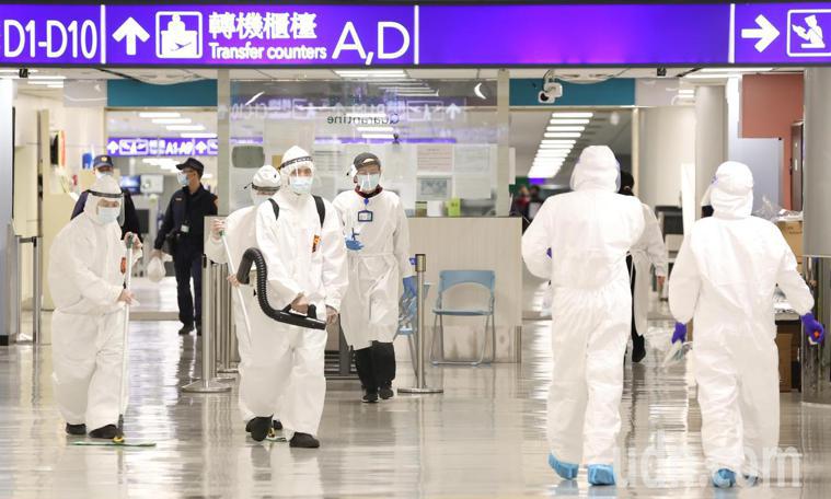 圖為機場旅客入境時經過的走道，工作人員穿著全套防護衣進行消毒。記者黃仲明／攝影