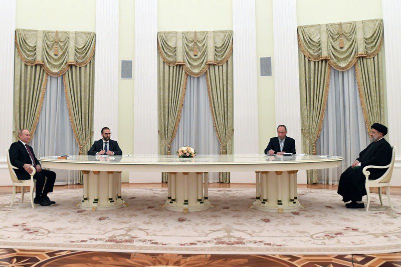俄國總統普亭（左）19日與到訪的伊朗總統萊希（右）會面，因防疫原因，兩人隔著長桌對談，相距約6公尺。美聯社