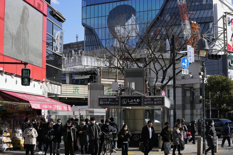 日本東京戴口罩民眾21日經過當地街頭。美聯社