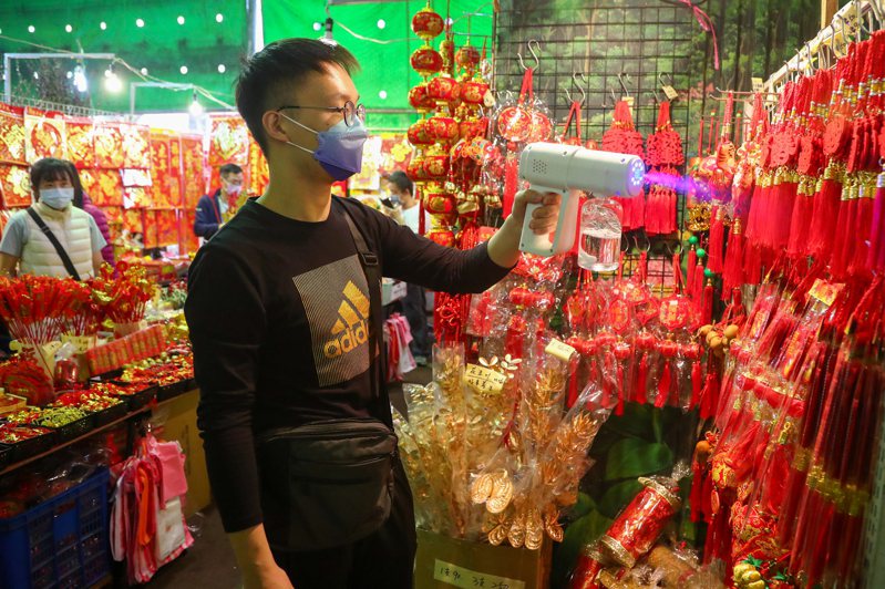因應國內COVID-19疫情升溫，台北建國花市賣春節飾品的商家加強環境消毒，落實防疫工作。 中央社
