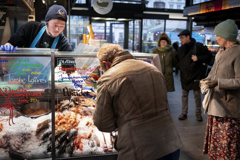 丹麥1月31日幾乎完全解除防疫措施，包括健康護照和強制戴口罩。圖為哥本哈根魚市場的顧客2月1日不再需要戴口罩。美聯社