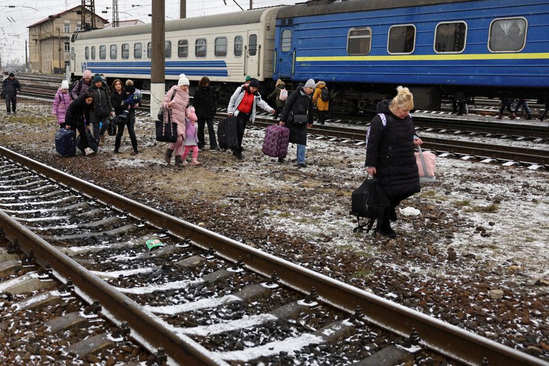 直达波兰边境的国家铁路持续运行，每个人发了疯似地要挤上这列车，车厢内挤得像罐头。图为乌克兰难民日前带着行李在火车轨道上行走逃离。路透(photo:UDN)