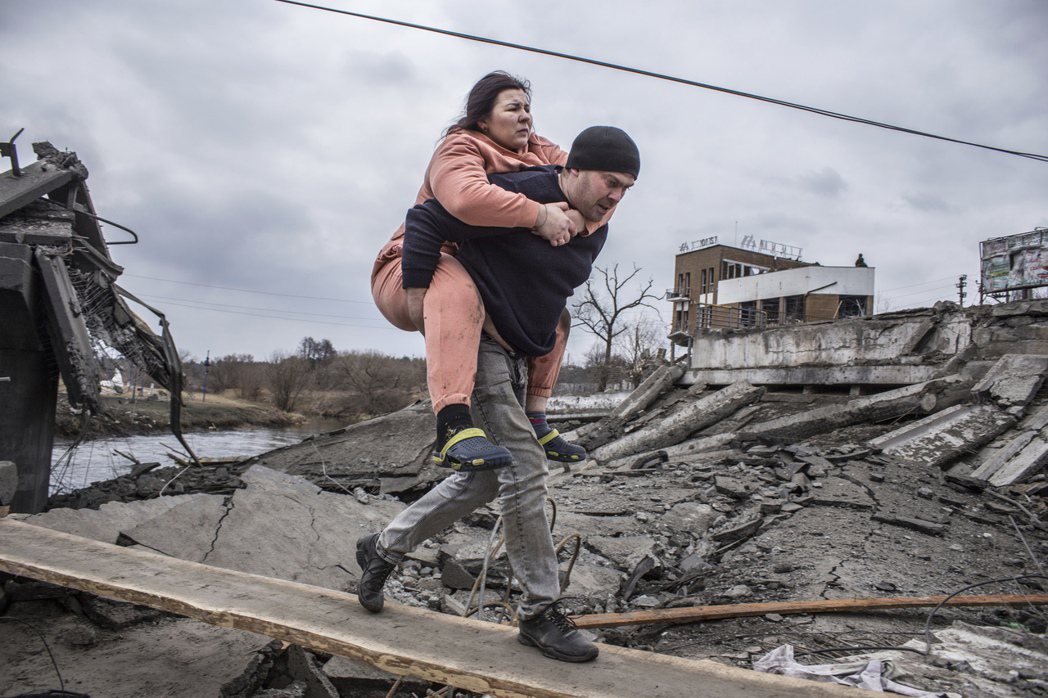 一名男子背著一名婦女穿越臨時小路，逃離烏克蘭伊爾平鎮。 美聯社