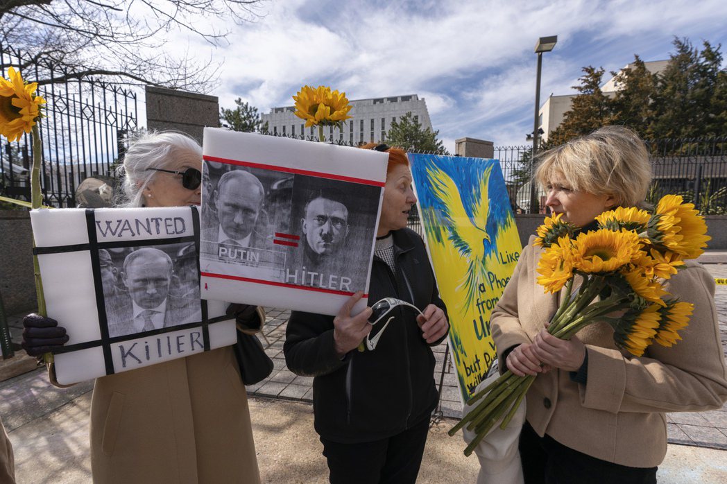 不少民眾在俄羅斯駐美國大使館前手持自製圖卡標語與烏克蘭國花向日葵聲援烏克蘭。 圖／美聯社
