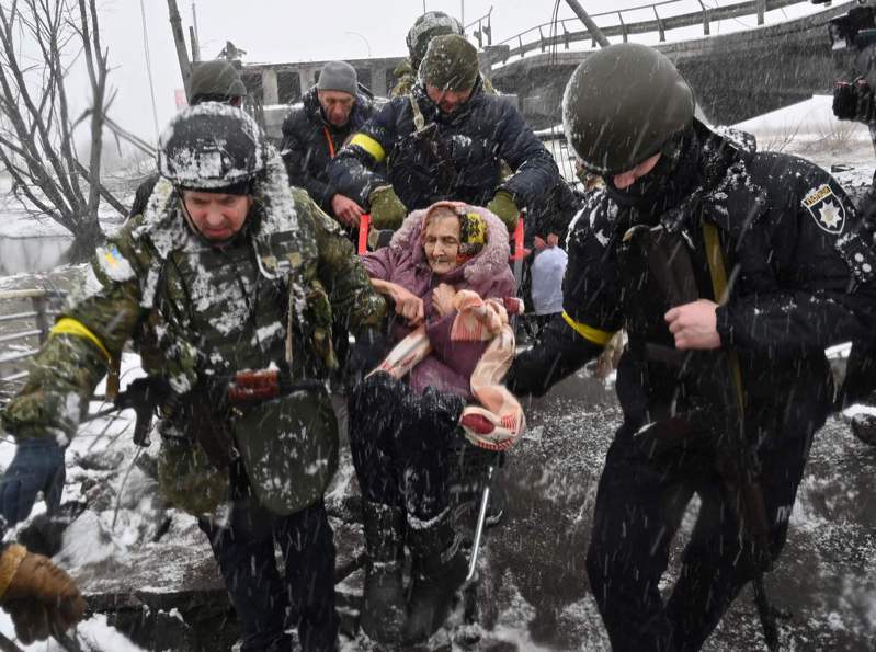雨雪中的战火 雨雪纷飞中，乌克兰军人八日在伊尔平协助一名年长妇人穿越毁损的桥梁。（法新社）(photo:UDN)