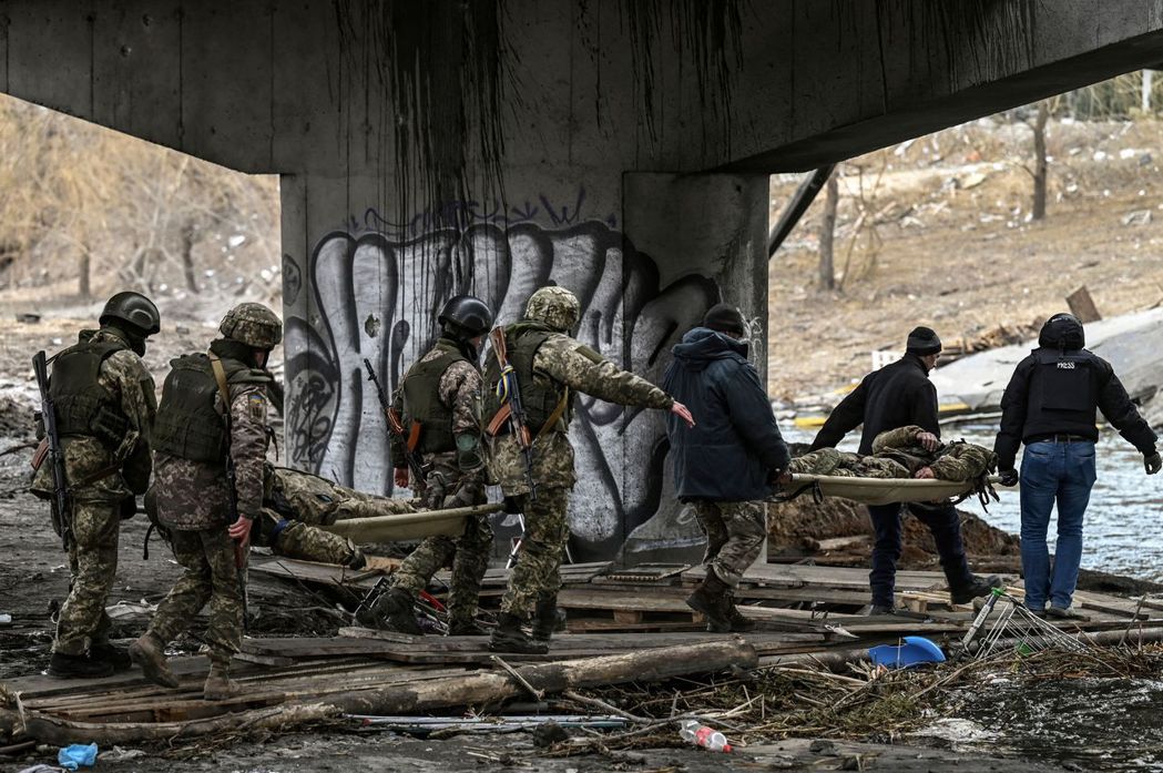 烏克蘭軍人在基輔西北部的伊爾平用擔架抬著同袍的遺體。 圖／法新社