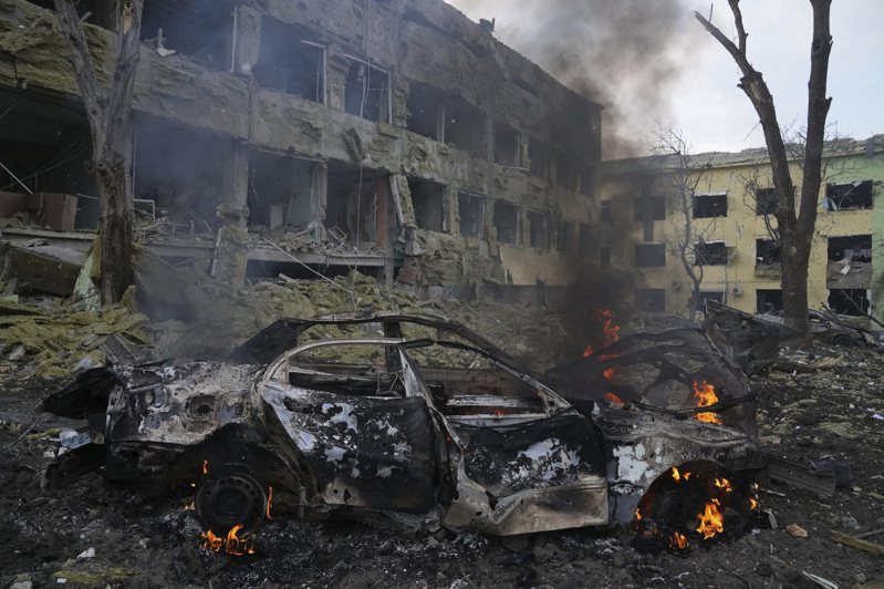圖為烏克蘭馬立波市一座婦幼醫院9日遭到俄軍砲擊，車輛在路邊燃燒。美聯社