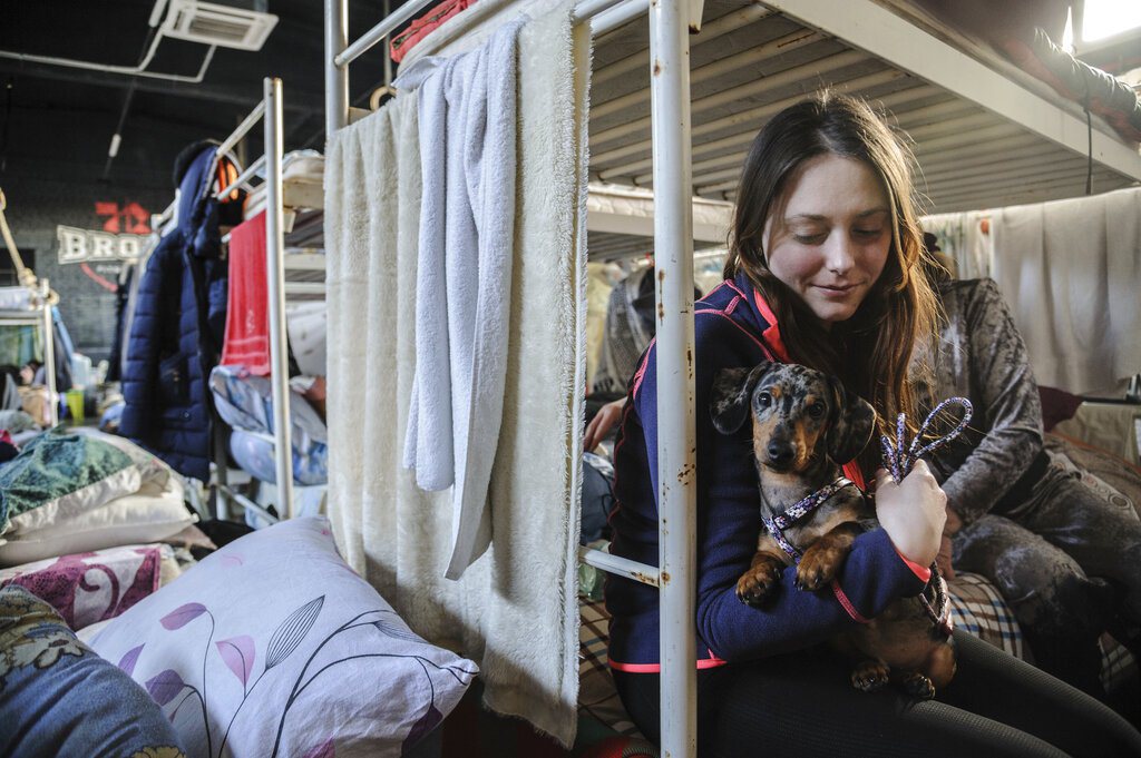 一名烏克蘭女子帶著她的狗暫居在由體育館改造成的避難處。 圖／美聯社