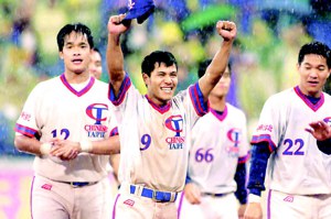 2001年3月25日中華隊王建明（中）冒雨演出雨中滑壘秀後，高舉雙手接受球迷歡呼。圖／聯合報系資料照片