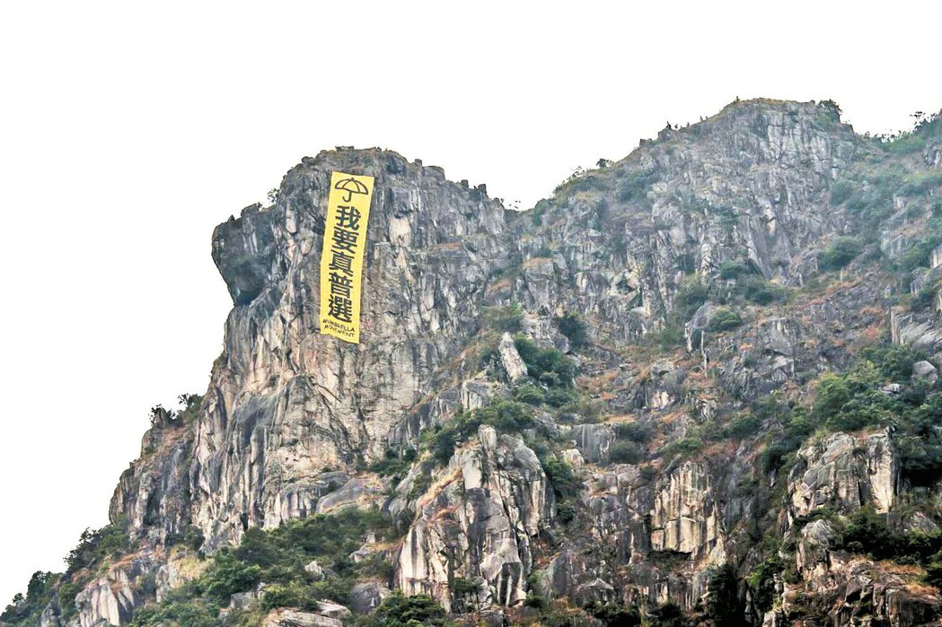 2014年，一群登山客在九龍獅子山掛上「我要真普選」的巨型標語條幅。 圖／路透社