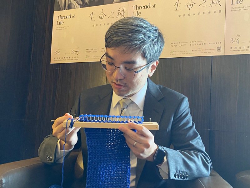 圖為南山人壽董尹崇堯（中）3月時出席「生命之織」攝影展感恩餐會，展示他替癌友編織的藍色圍巾。記者陳怡慈/攝影