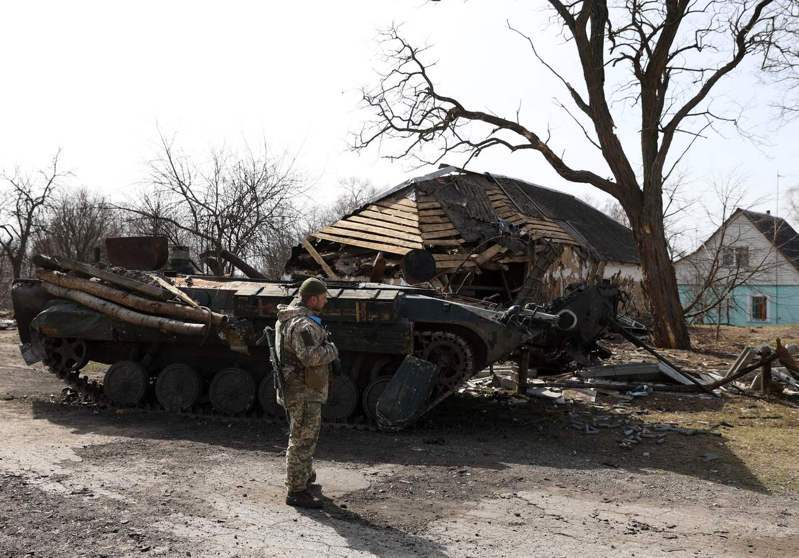 一名乌克兰士兵3月28日站在毁损的俄国装甲运兵车前。法新社(photo:UDN)