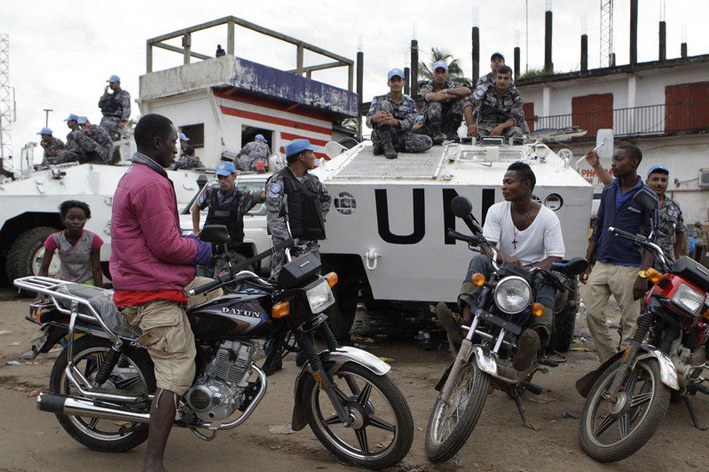 赖比瑞亚首都蒙罗维亚的摩托计程车司机，在联合国装甲运兵车旁等客人上门。（美联社）(photo:UDN)