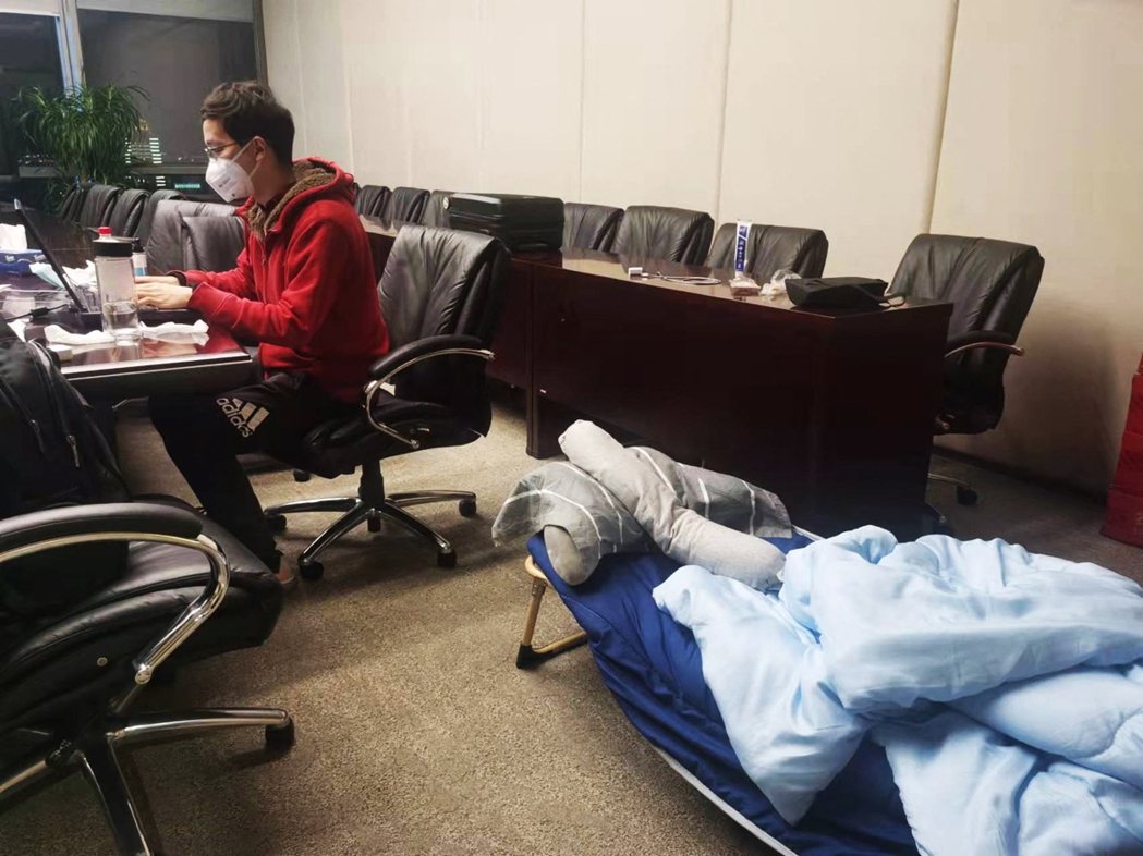圖為上海的交通銀行一名員工在辦公室就地隔離，在行軍床旁邊工作。 圖／路透社