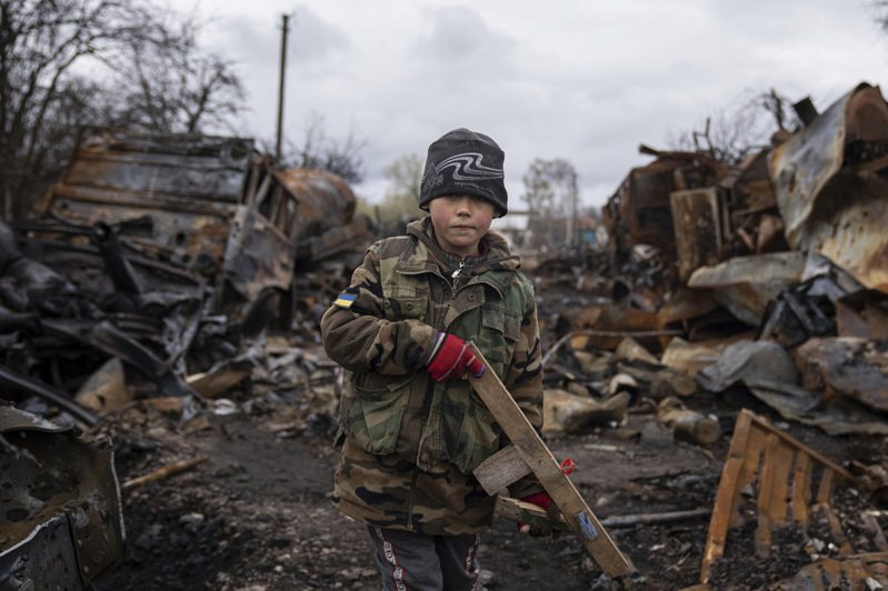一名乌克兰儿童十七日在北部城市切尔尼戈夫近郊被毁的俄国军车旁拿着木制玩具枪。（美联社）(photo:UDN)