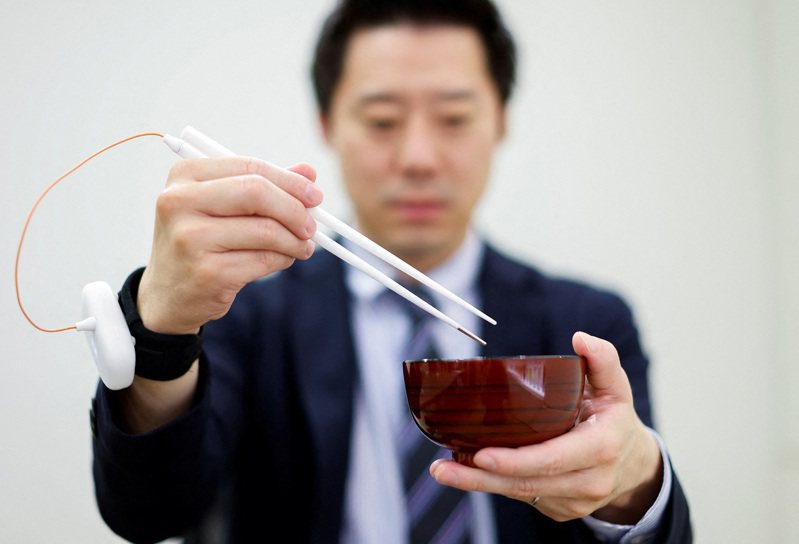 麒麟控股一位职员正示范使用该公司与明治大学教授宫下芳明共同开发、可以提升食物味道的「增味筷子」，摄于15日。路透(photo:UDN)