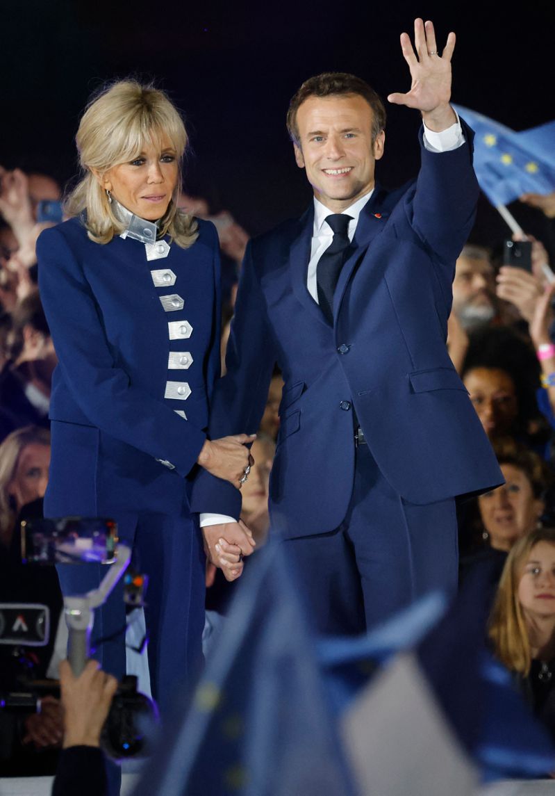 法國總統馬克宏（右）廿四日在巴黎戰神廣場與夫人碧姬攜手慶祝連任成功。（法新社）