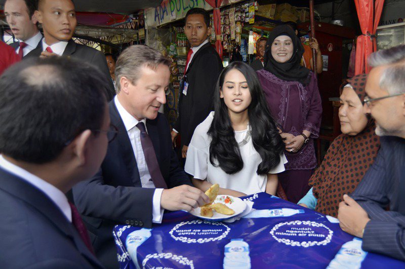 阿雲達（中，白衣者）2015年7月陪來訪的英國首相卡麥隆（左二）在雅加達路邊攤吃點心。美聯社