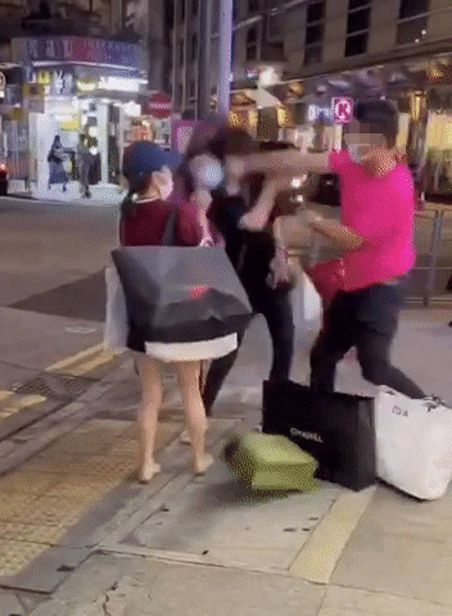 網上瘋傳影片，顯示有穿熒光粉紅色短袖上衣的男子，在街頭連環拳打一名穿黑衣的女子。（影片截圖）