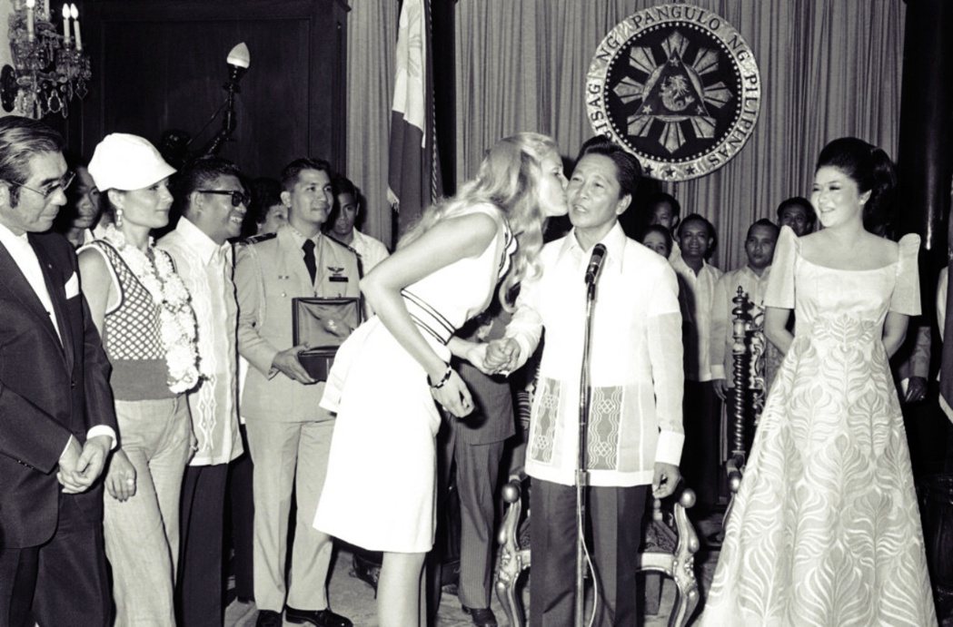 1974 年 7 月 16 日，美國選美小姐在拜訪馬尼拉時親吻馬可仕總統。當時，...