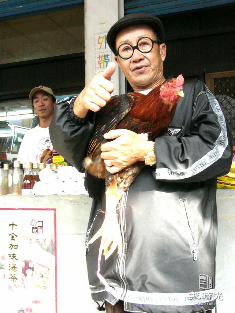 老牌諧星脫線抱著他養的「讚鬥雞」說，台東放山雞完全未受禽流感風暴影響，他的「脫線牧場」新春生意比往年更好。 日期：2004/02/01。攝影：周全剛。 來源：聯合報