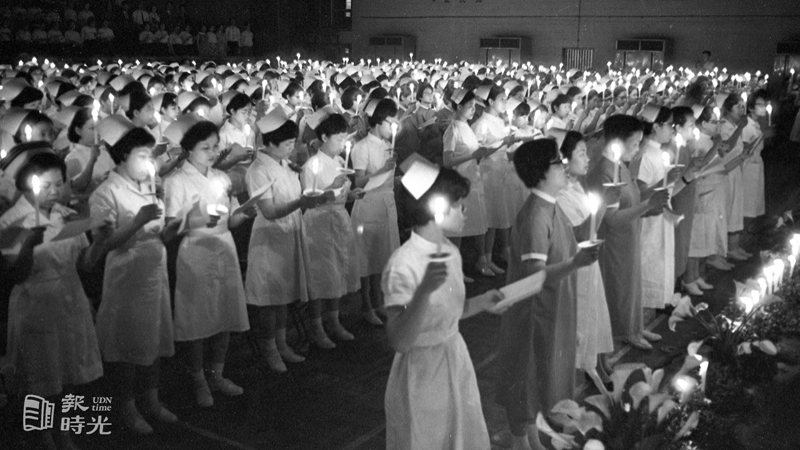 圖說：國際護士節慶祝大會，十二日晚間在台北市省立護專禮堂舉行燭光晚會，圖為護專學生、與會護士手持蠟燭，燭光搖曳會中，景象相當聖潔、純淨。來源：聯合報。攝影：龍啟文。日期：1970/05/12
