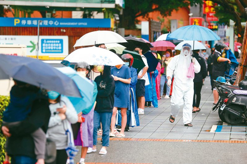 周末梅雨鋒面報到，民眾撐著傘在衛福部台北醫院排隊做PCR，隊伍長到圍繞半個院區。圖／聯合報系資料照片