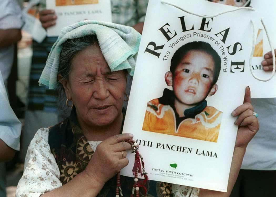 西藏人民舉著失蹤的第十一世班禪喇嘛更登確吉尼瑪的照片。 圖／美聯社