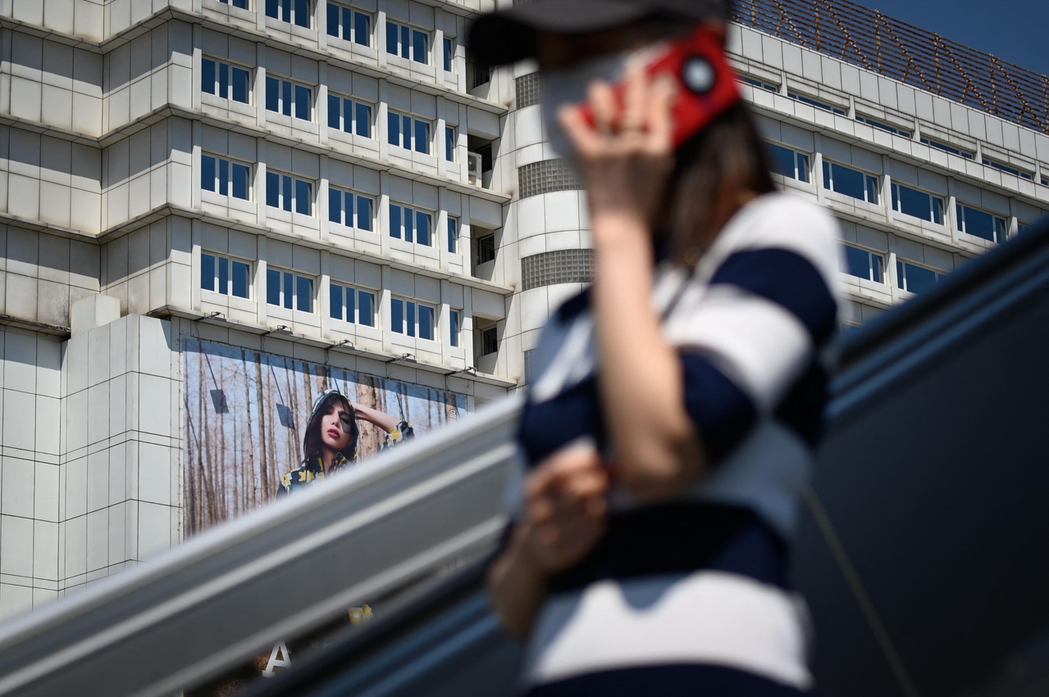 圖為北京街頭一名女子正在邊走邊講手機。法新社