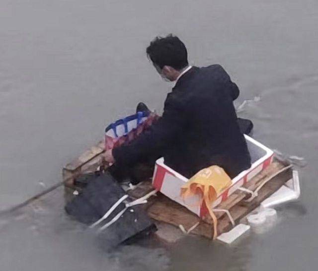 「遠離上海」，一名穿西裝的男子自製簡易船打算划船回到老家江西。（搜狐）