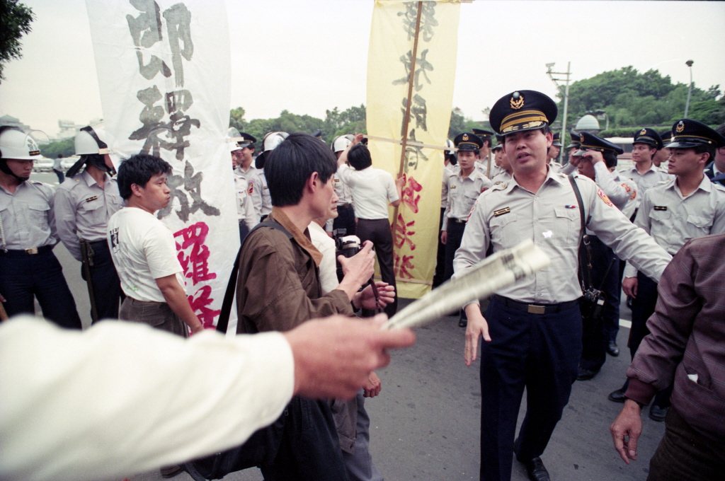 1990年4月9日，台灣基督長老教會的「教會與社會委員會」，九日在台北市遊行，隊伍中兩名男子高舉「立即釋放羅益世」、「釋放所有政治犯」大旗，欲走向總統府，但在介壽路、公園路口，即遭警方阻擋。 圖／聯合報系