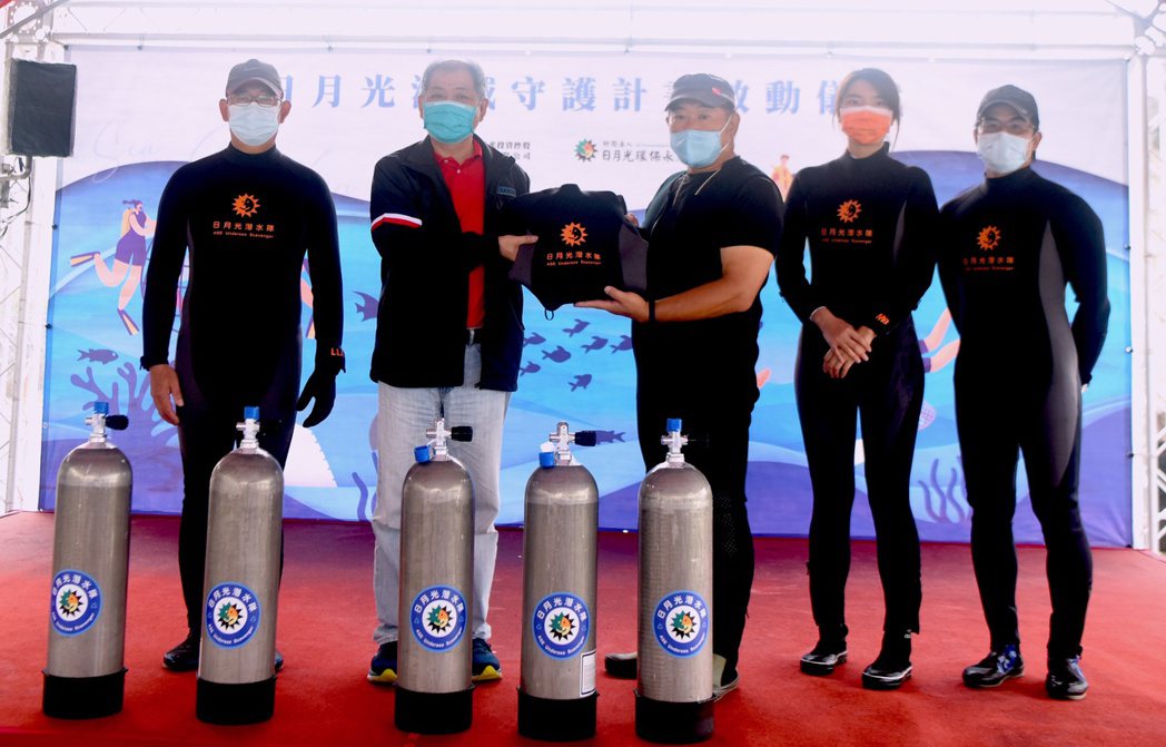 龍洞灣公園總教練尹德成（右三）代表接受印有日月光字樣的防寒衣、氣瓶，為日後淨海增...