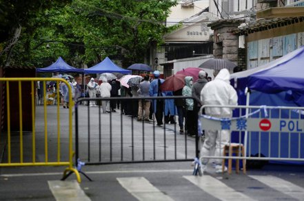 上海因疫情實施封控，導致4月經濟活動急劇萎縮。圖為上海封控區內民眾接受核酸檢測。（路透）