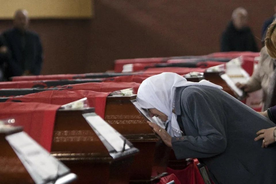 死於科索沃戰爭的阿裔居民棺材上蓋著阿爾巴尼亞旗，一名女子在葬禮上悲傷哭泣。 圖／...