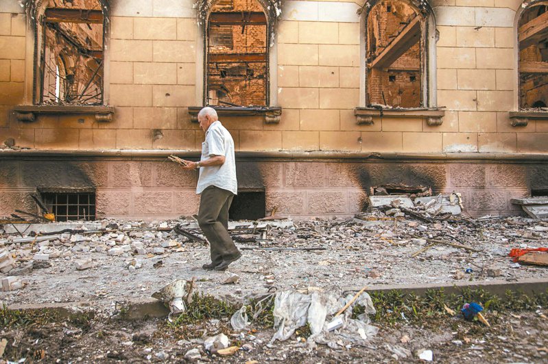 乌东卢甘斯克的利西昌斯克一名男子十日经过一座遭空袭破坏的大楼。（路透）(photo:UDN)