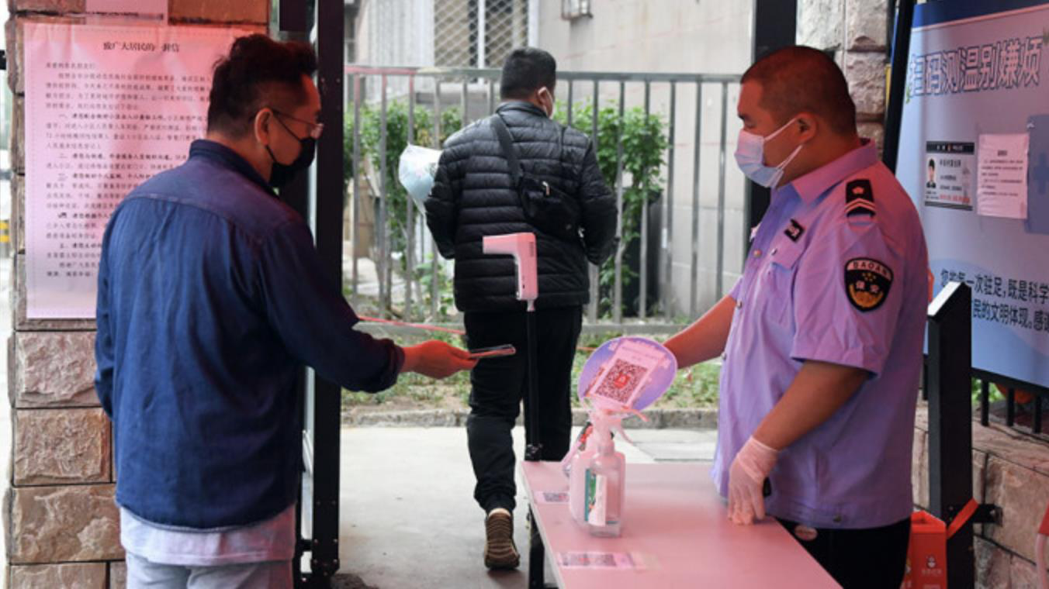 北京保全人員查看進入住宅小區人員的「健康寶」信息。（新華社照片）